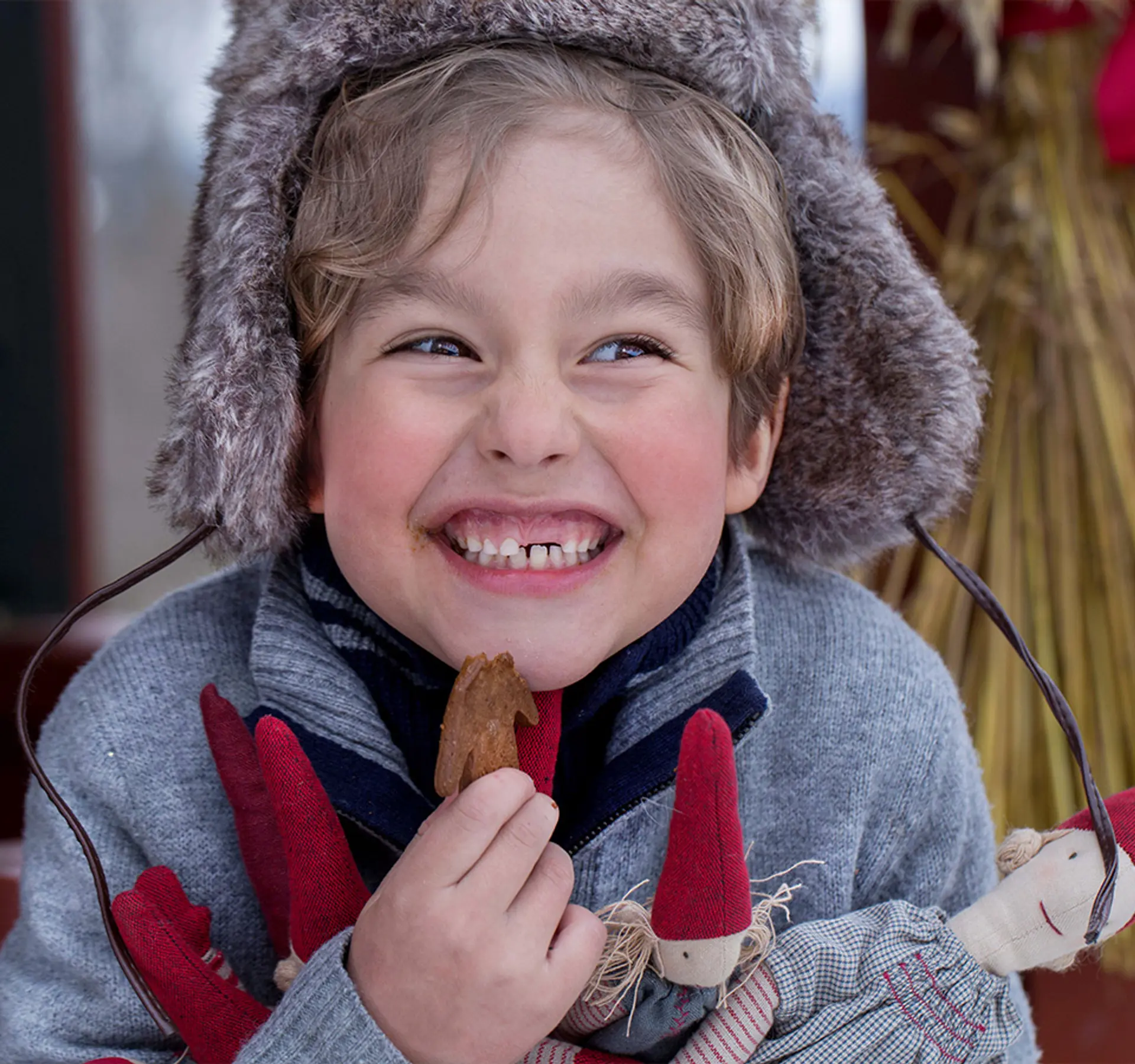 Fotografi av en gutt som smiler med en pepperkake og nisser i hendene. Trykk videre for å se mer til adventskosen.