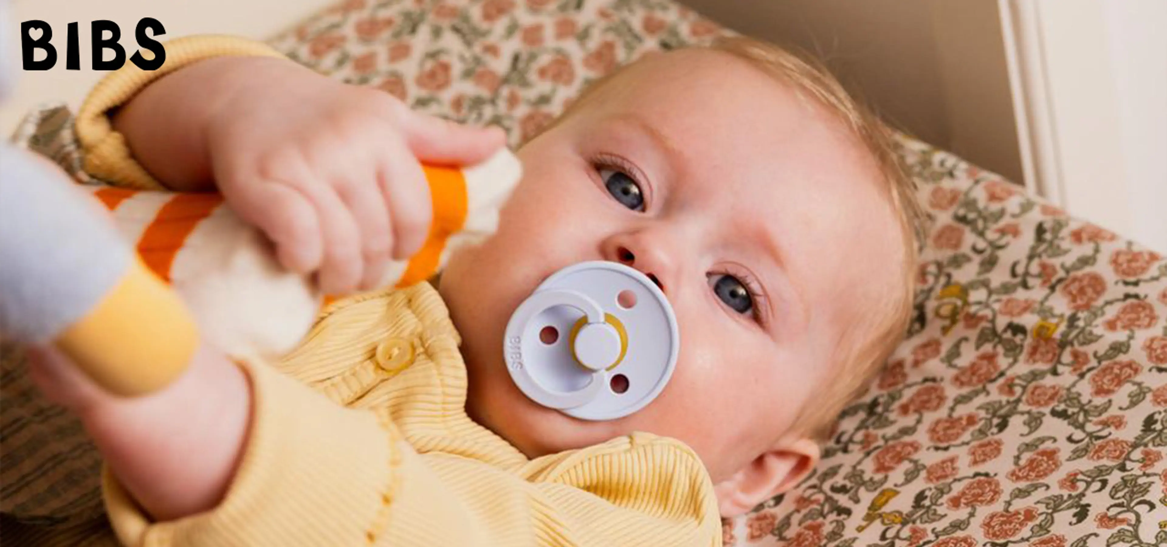 Fotografi av baby med BIBS smokk i munn.