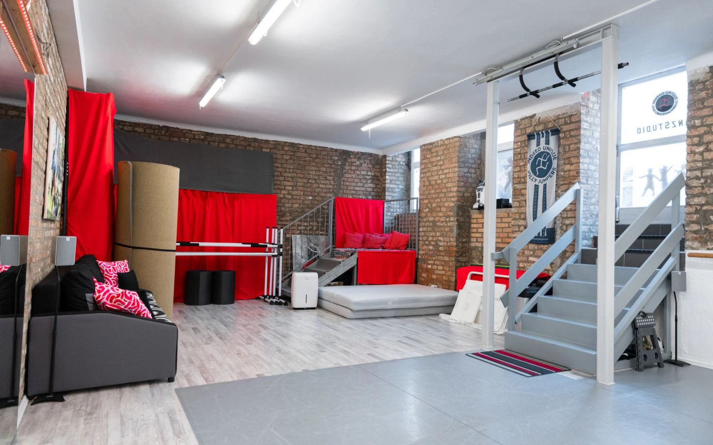Studio „Unique“: Ecke mit Couch, Matten, Klimmzugstange und Treppe