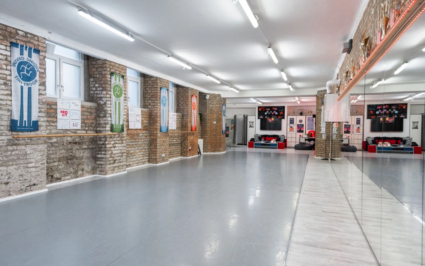 Studio „indeed“: Blick durch den Saal mit Ballettstangen und Spiegeln zum Aufenthaltsbereich