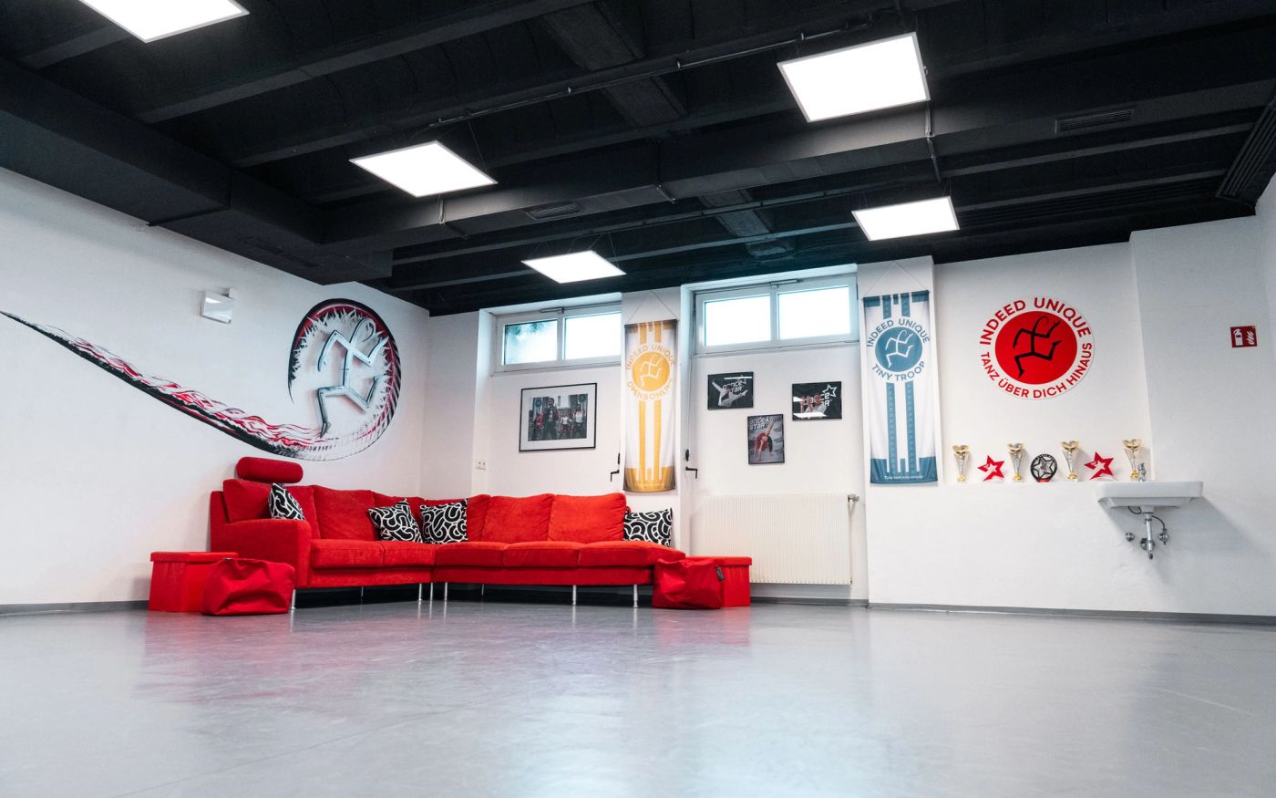 Light Floor: rotes Sofa vor der Wand mit Logo und Bannern