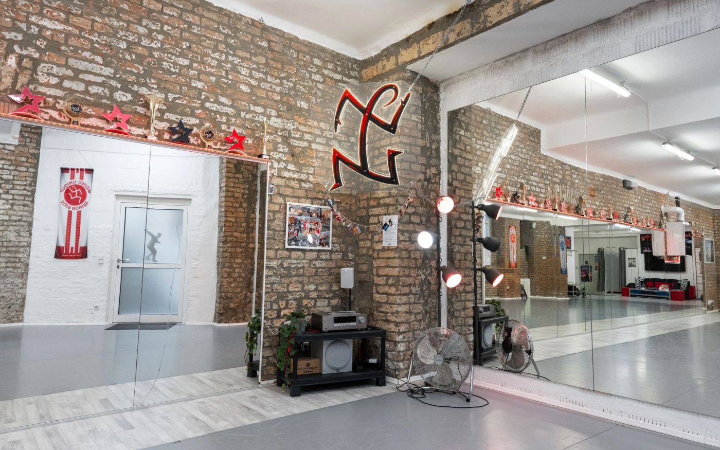 Studio „indeed“: Ecke mit Logo an der Ziegelwand, Musikanlage und Eingangstür