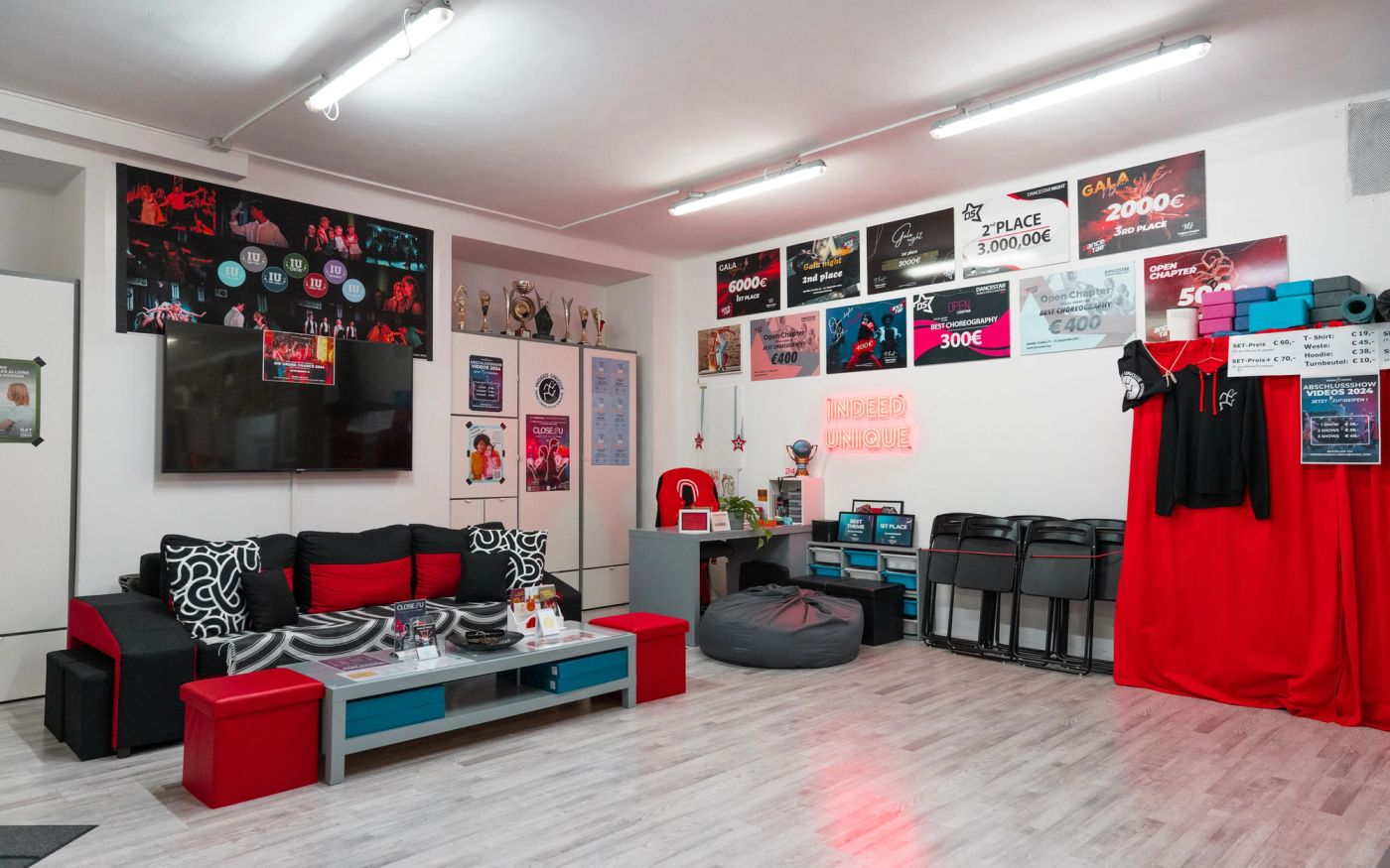 Aufenthaltsbereich in Wien: Couch mit Flatscreen, Sitzplätze und Siegerschecks an der Wand