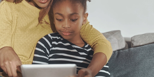 A mother and child working together on an iPad.