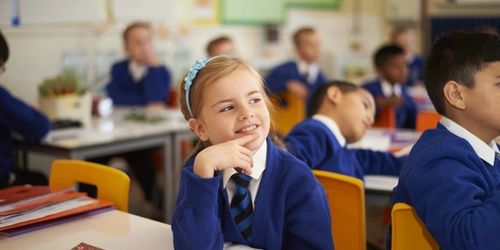 A learner at Queens Church of England Academy in the classroom, smiling.