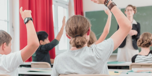 Learners raising their hands in class
