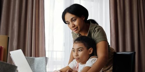 A parent and child learning together on a laptop