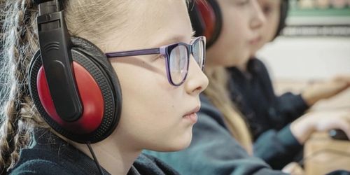 Learners wearing headphones and working on computers at Wath Victoria Prrimary School.