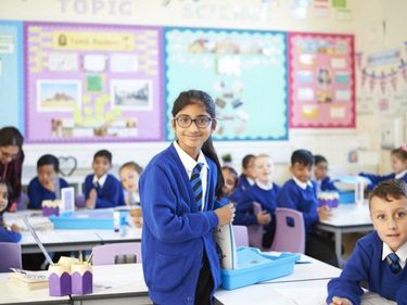 Learners at Queens Church of England Academy in a classroom, smiling at the camera.