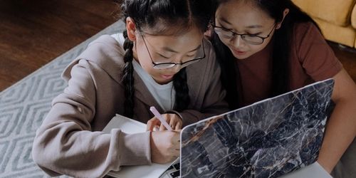 A parent and child working on literacy on a laptop together