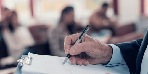 A teacher writing while watching a class of students