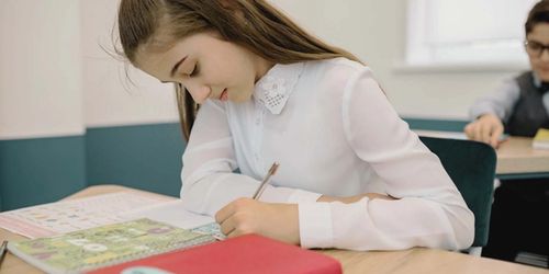 A learner reading and writing in a classroom