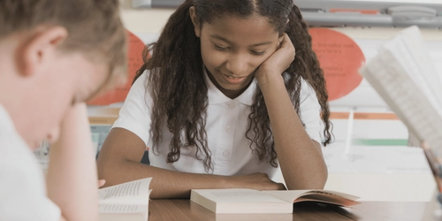 Two learners reading across the table from one another.