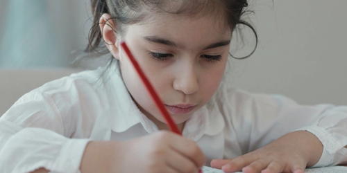 A student learning academic vocabulary and writing on paper.