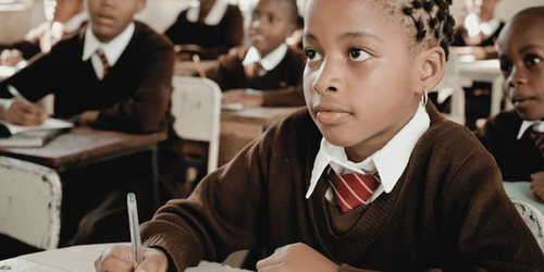 A learner writing while being taught non-fiction in the classroom.