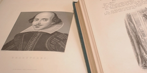 An open book showing a picture of William Shakespeare and one of his texts.