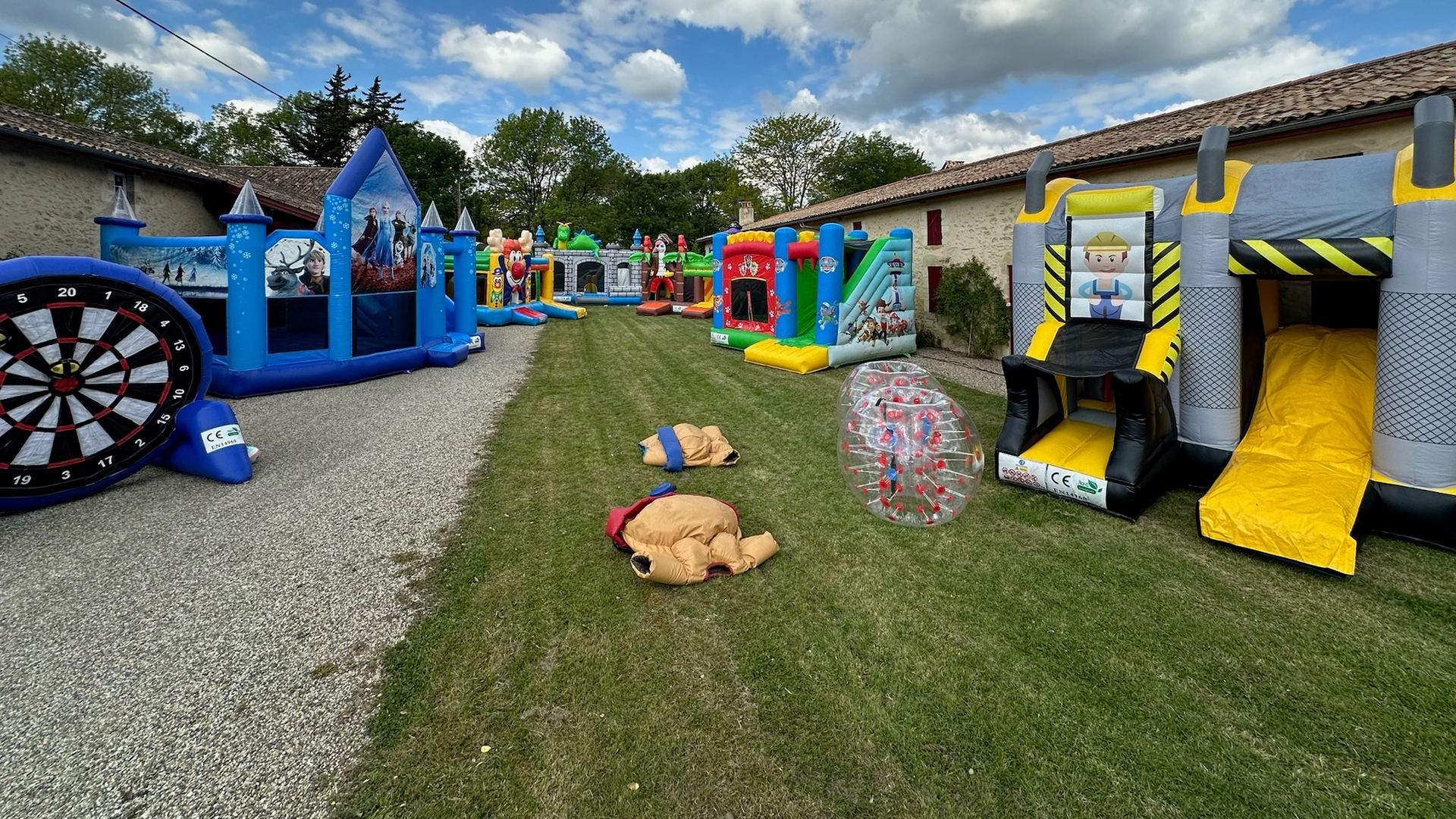 Parc de structures gonflables LOUTAFETE — châteaux, cible géante et bubble foot installés dans le jardin entre les deux bâtisses