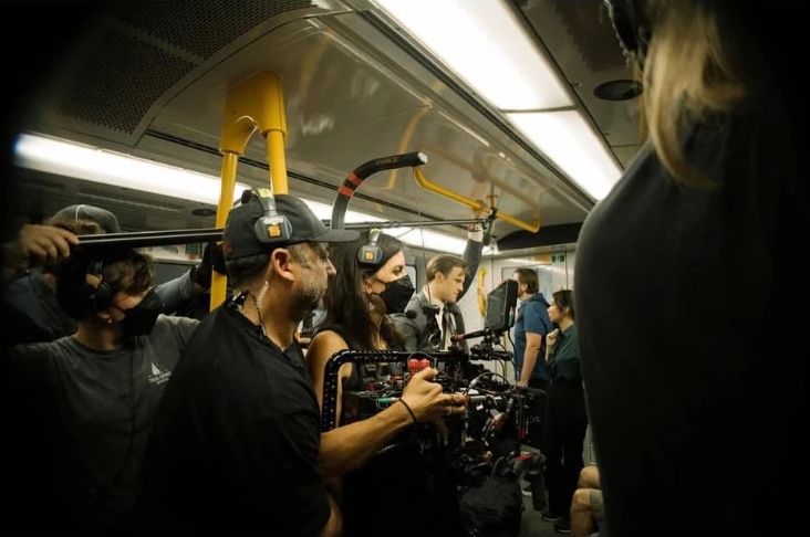 Behind the scenes: the camera crew filming in a crowded train carriage.