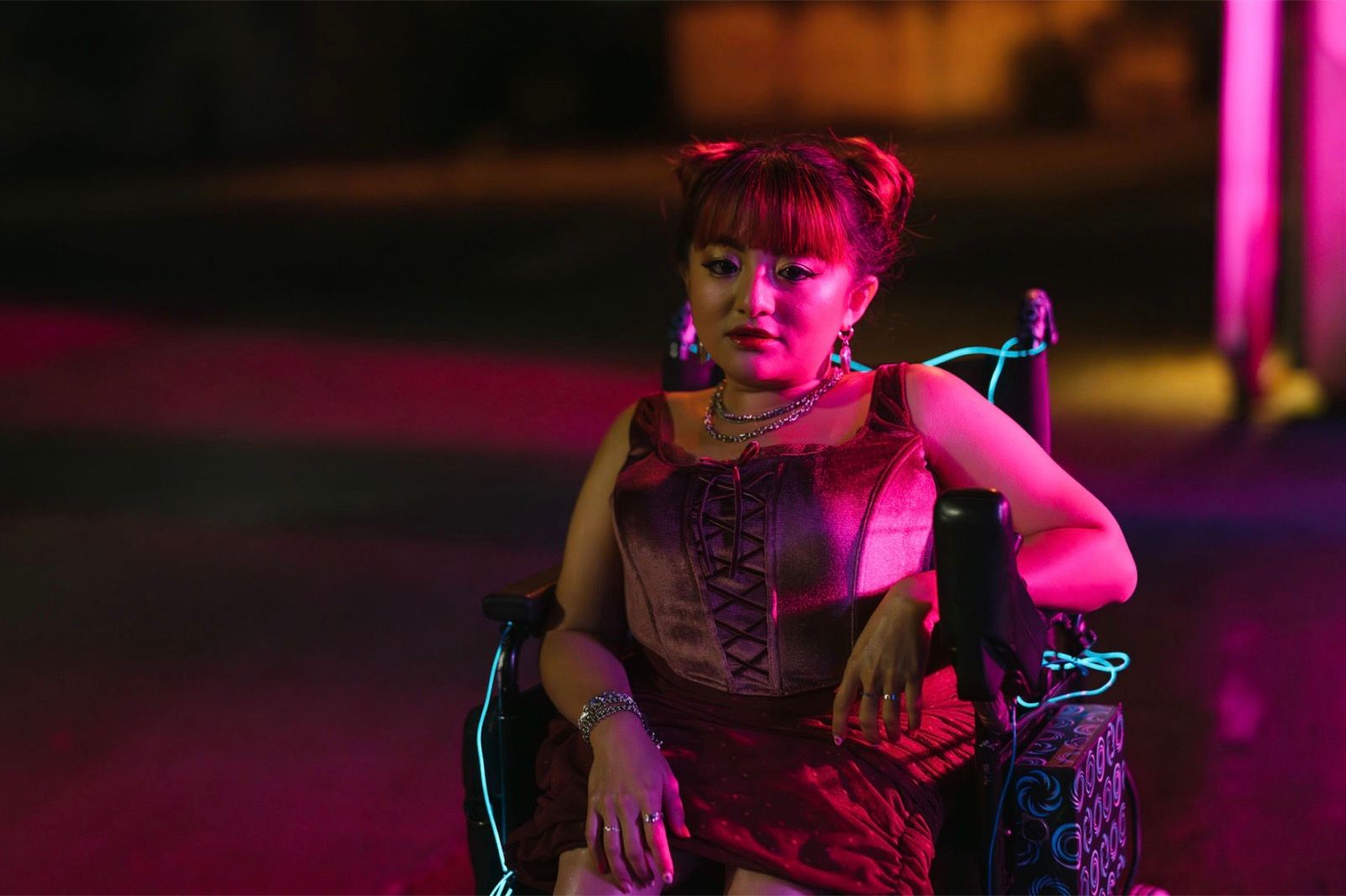 A woman in a wheelchair in magenta light.