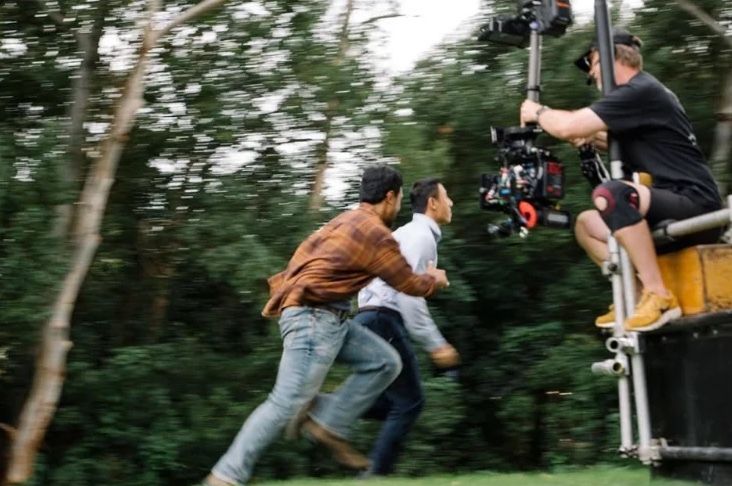 Behind the scenes: two actors run past the camera, mounted high on a crane, through bushland.