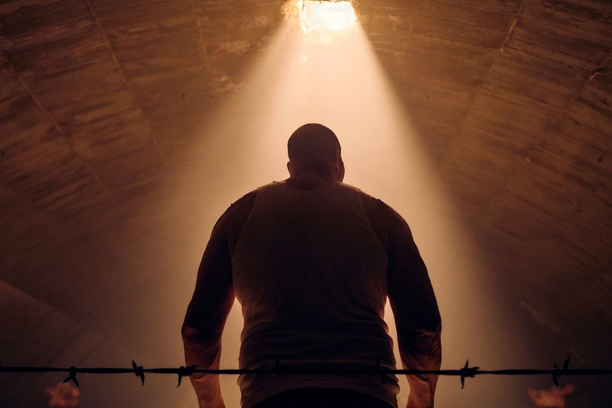 A boxer seen from behind in a shaft of light, underground.