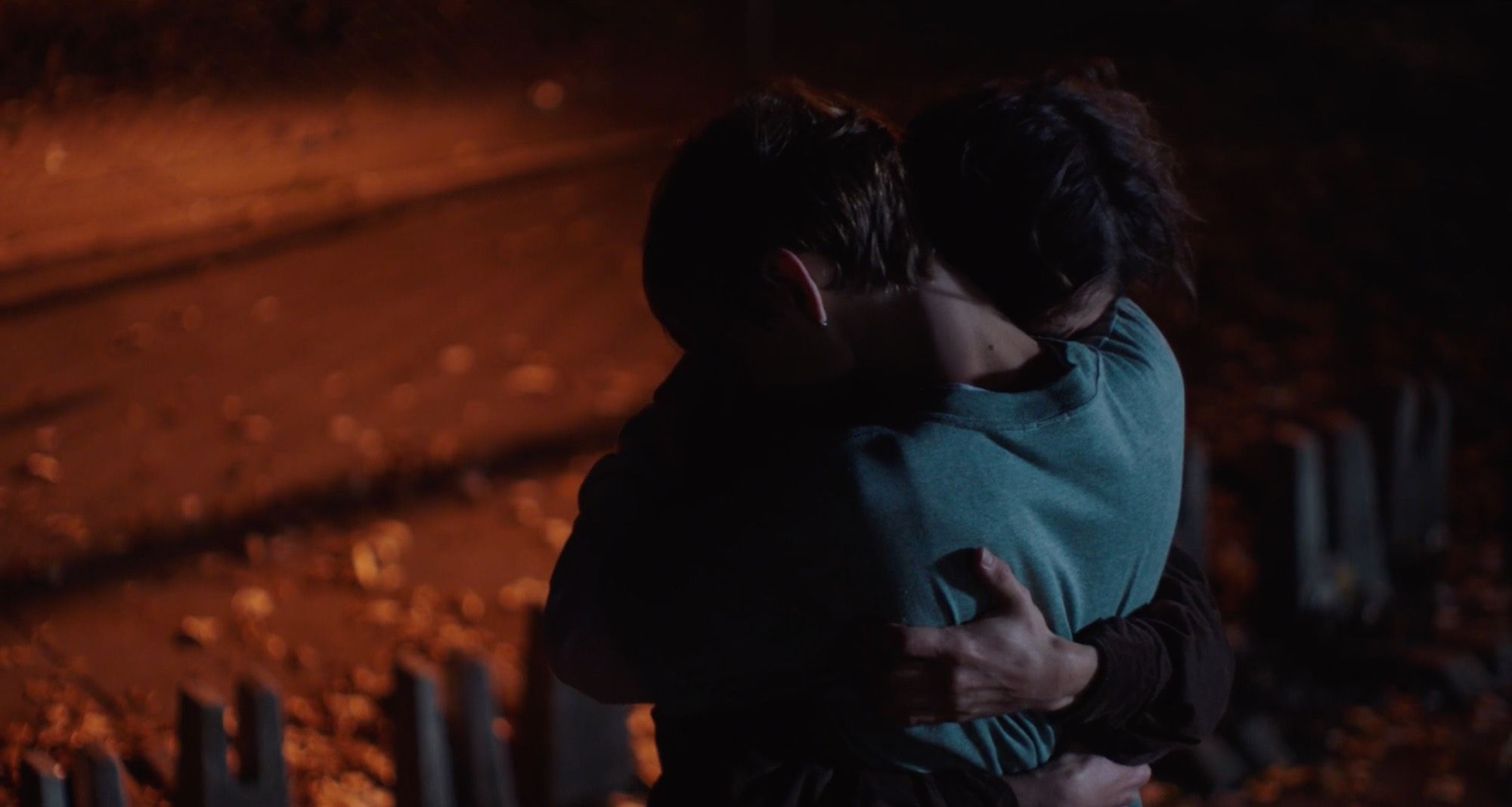 Laura: two young men embrace in red light.