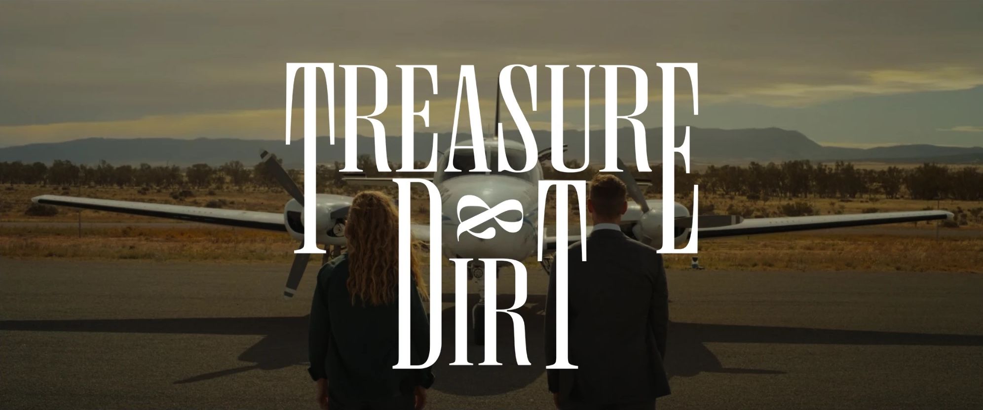 The Treasure & Dirt title over two detectives, seen from behind, facing a small plane on an outback airstrip.