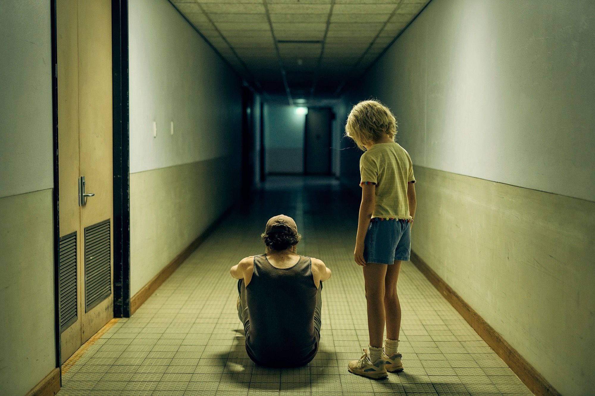 Figures in a long green institutional corridor.
