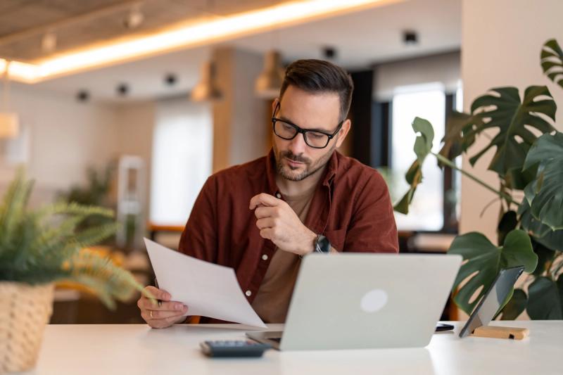 Man reviewing business account options with a piece of paper and a laptop