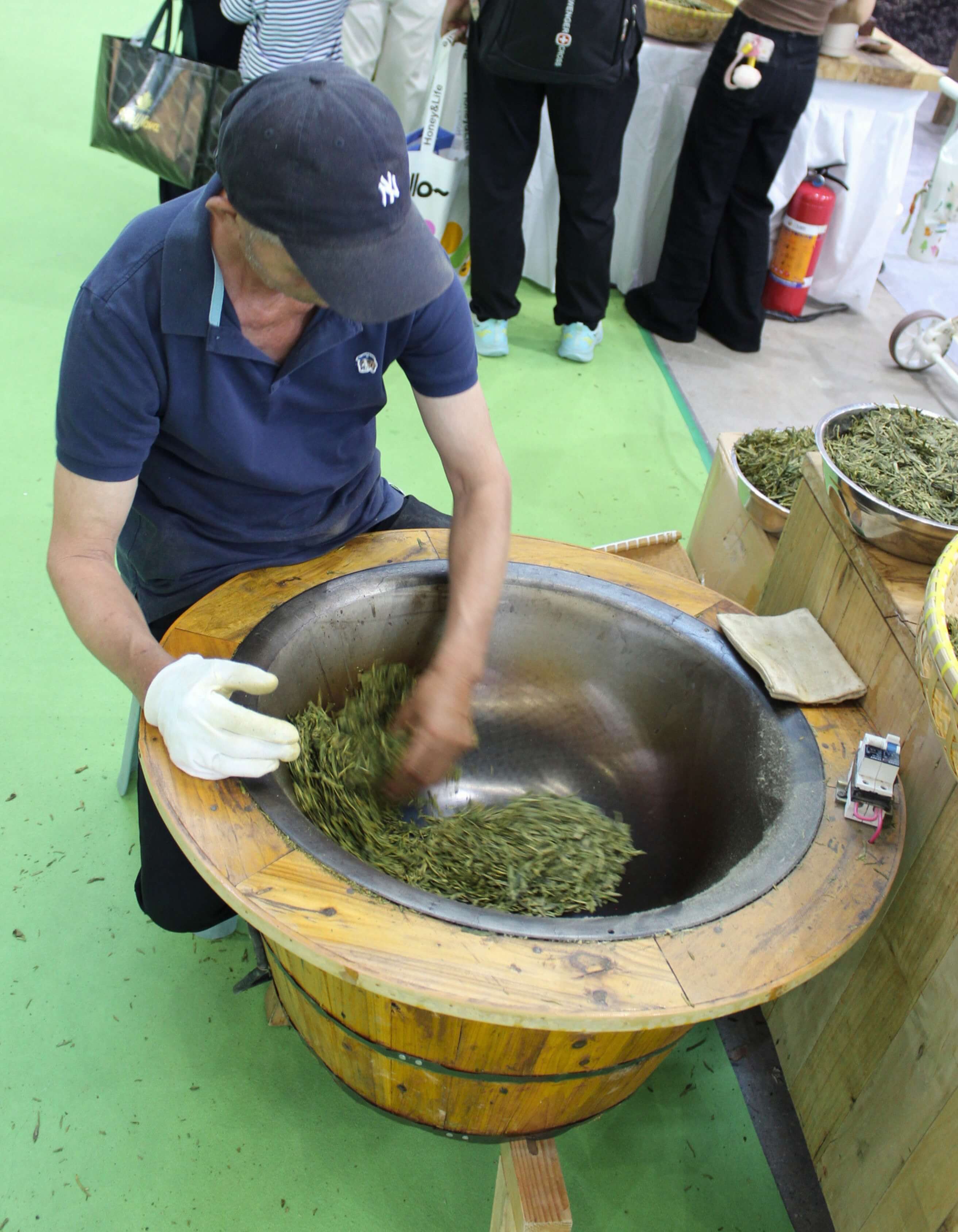A man pan-firing green tea by hand in a wok.