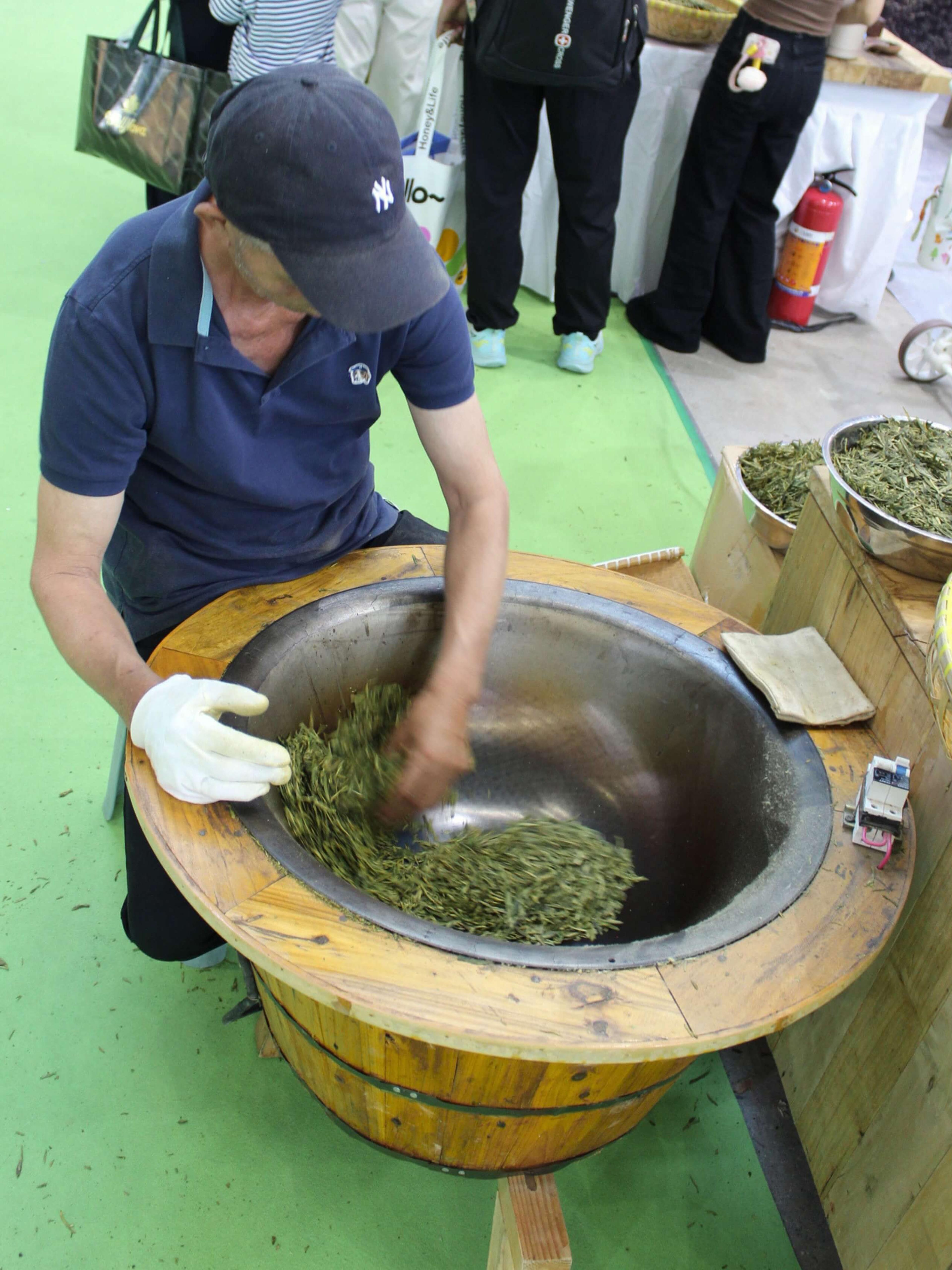 A man pan-firing green tea by hand in a wok.