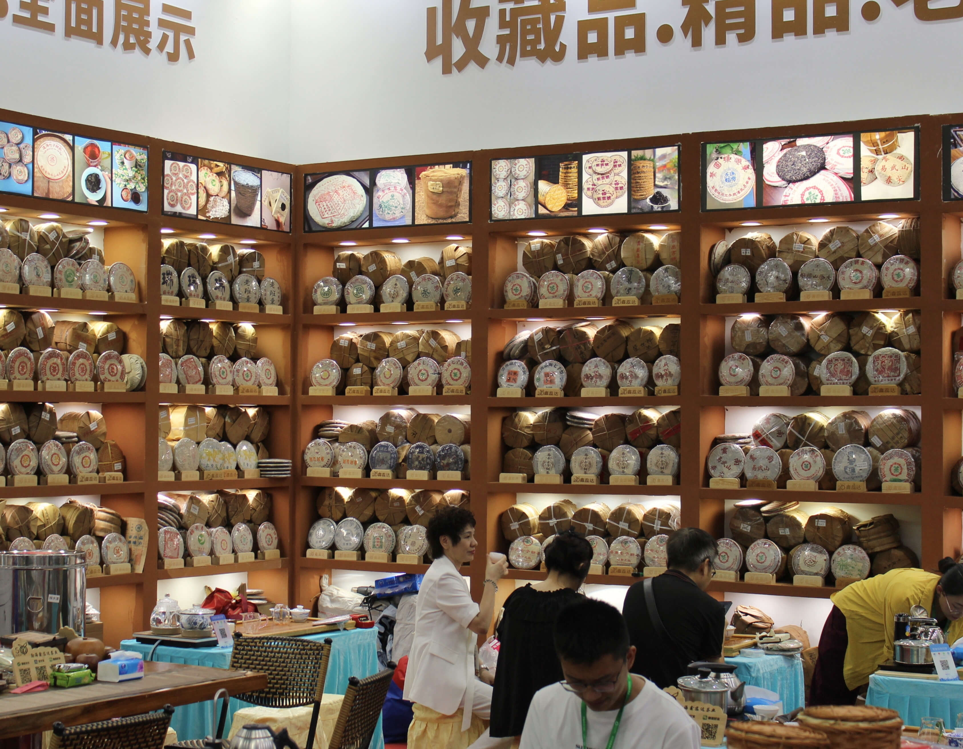 A booth wall stacked floor to ceiling with paper-wrapped puer cakes, some decades old.