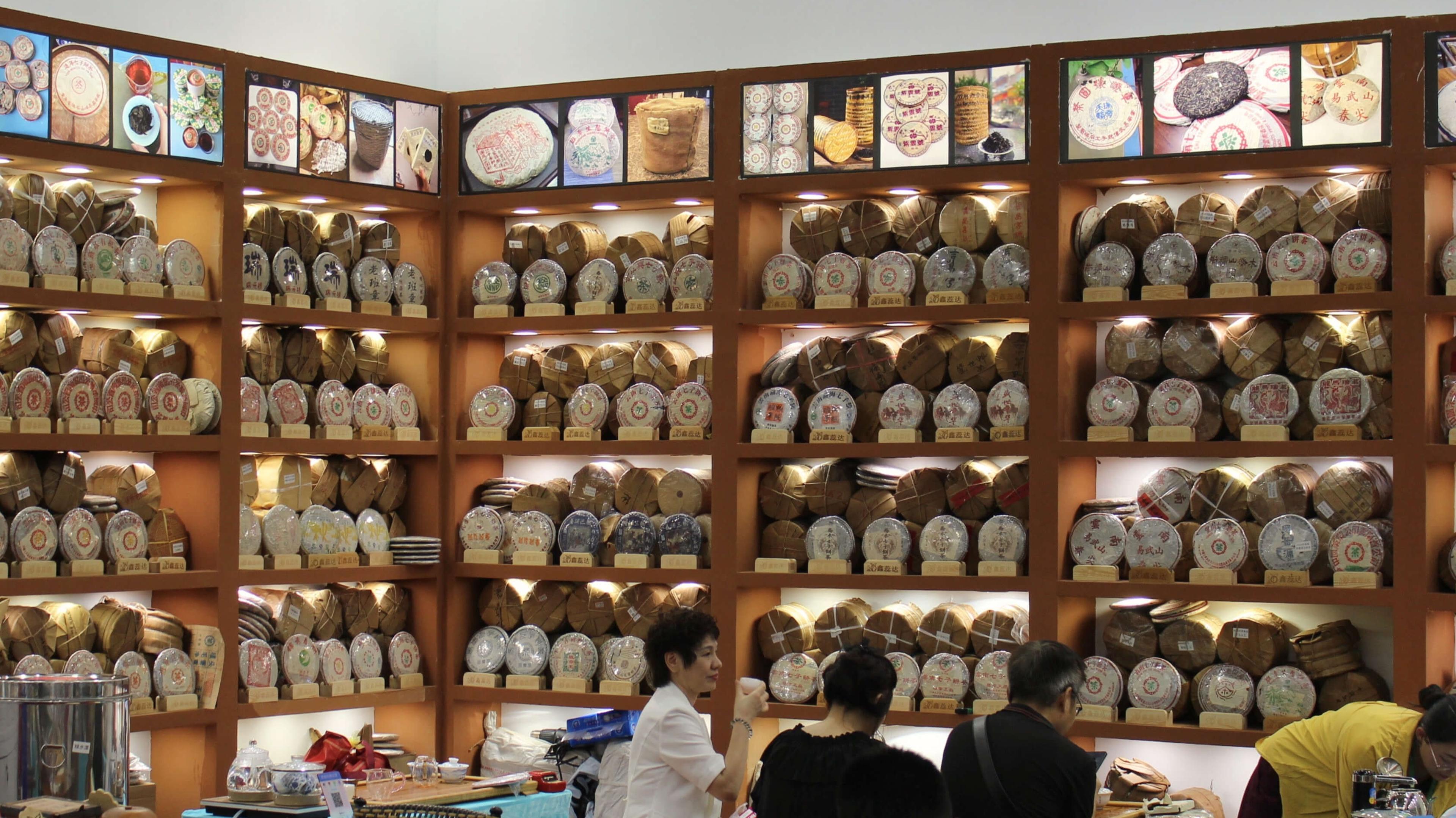 A booth wall stacked floor to ceiling with paper-wrapped puer cakes, some decades old.