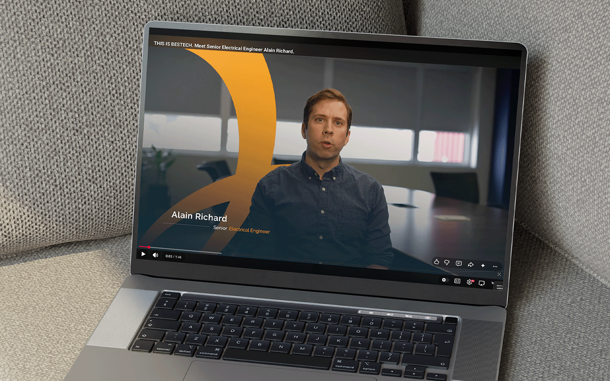 Laptop displaying a video of a Bestech senior electrical engineer speaking to camera in an office setting, with name and title overlay.
