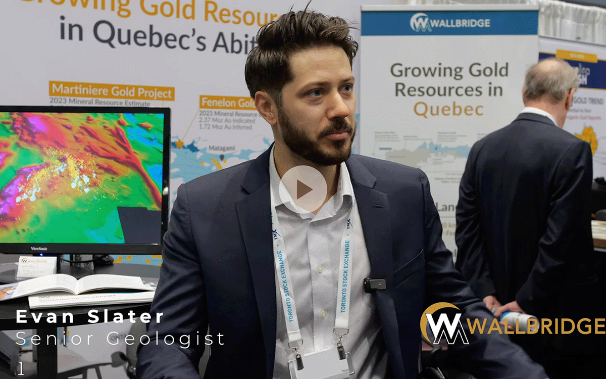 Video thumbnail of a Wallbridge Mining geologist being interviewed at a trade show booth, with gold project maps and branding in the background.