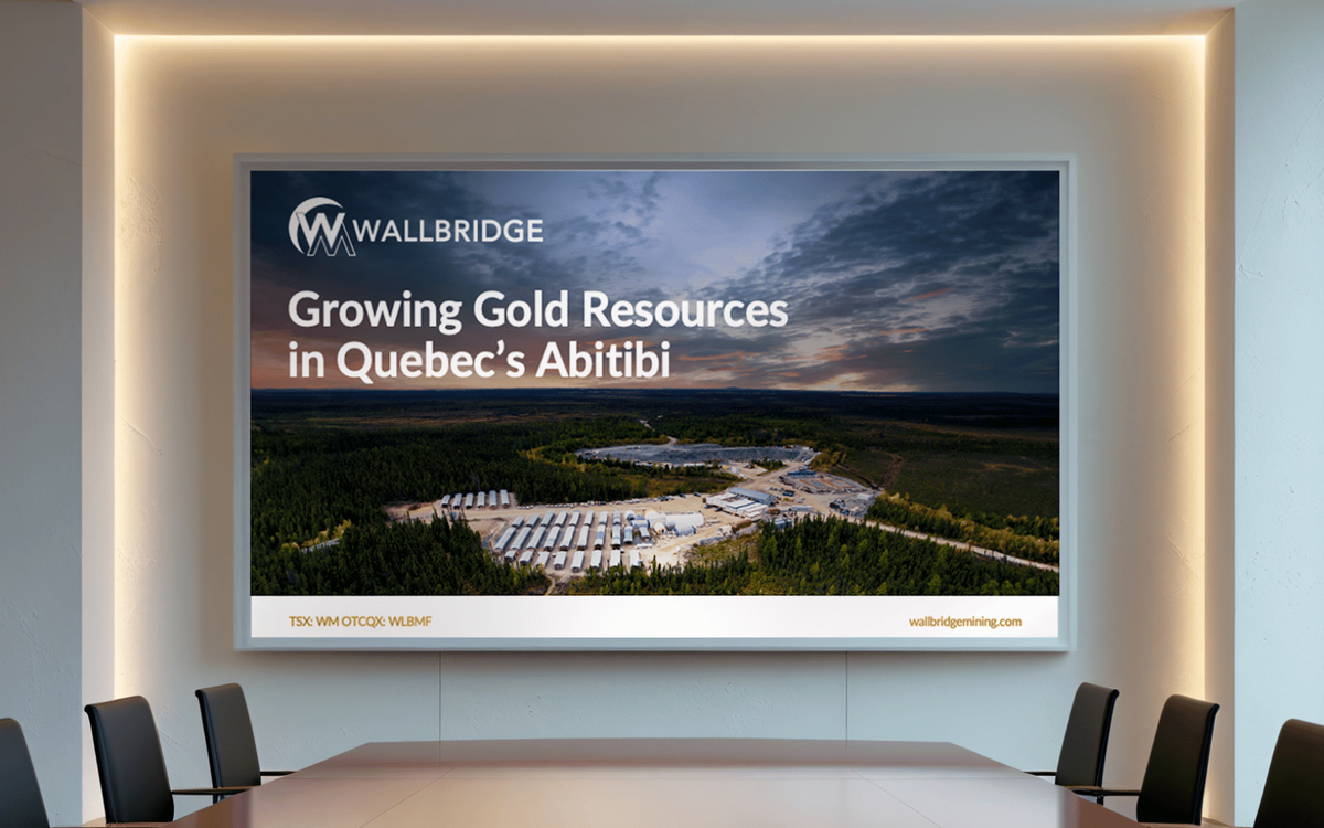 Boardroom screen displaying a Wallbridge Mining presentation title slide with an aerial photo of a gold mining site in Quebec's Abitibi region."
