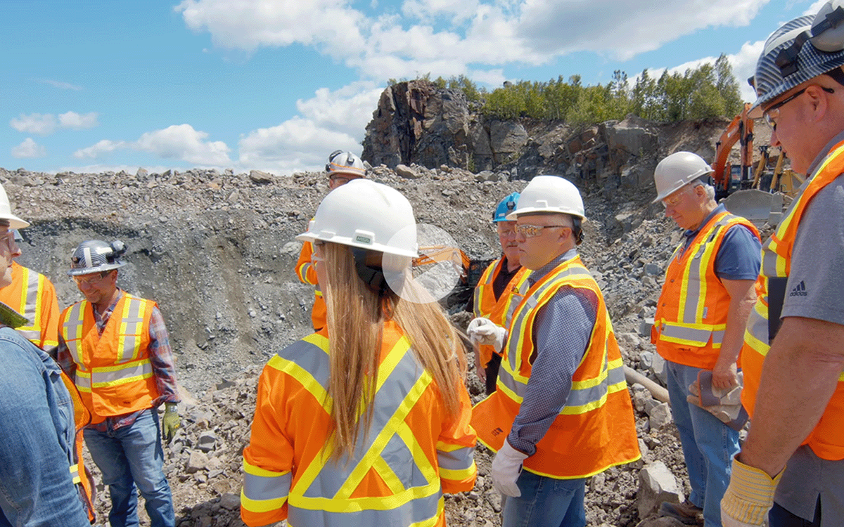 Video thumbnail of a group in hard hats and safety vests standing at a mining site during a guided site tour.