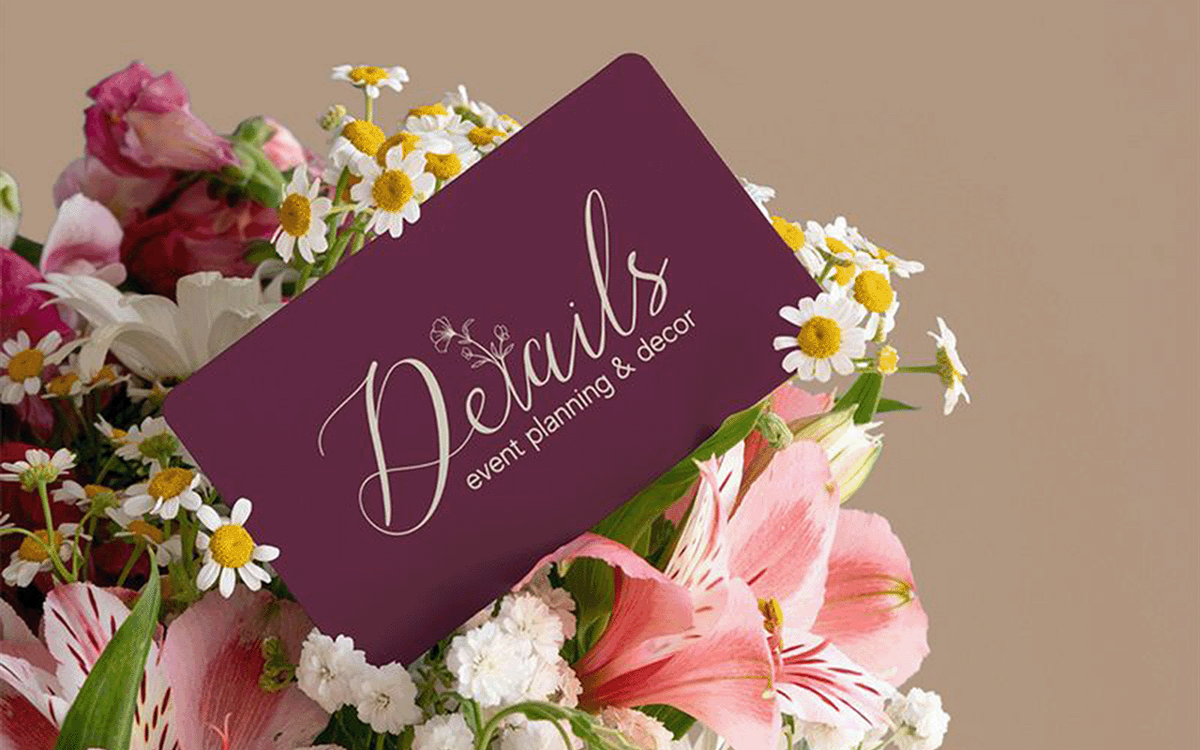 Business card for Details Event Planning & Decor in an elegant script logo, nestled among pink and white flowers.
