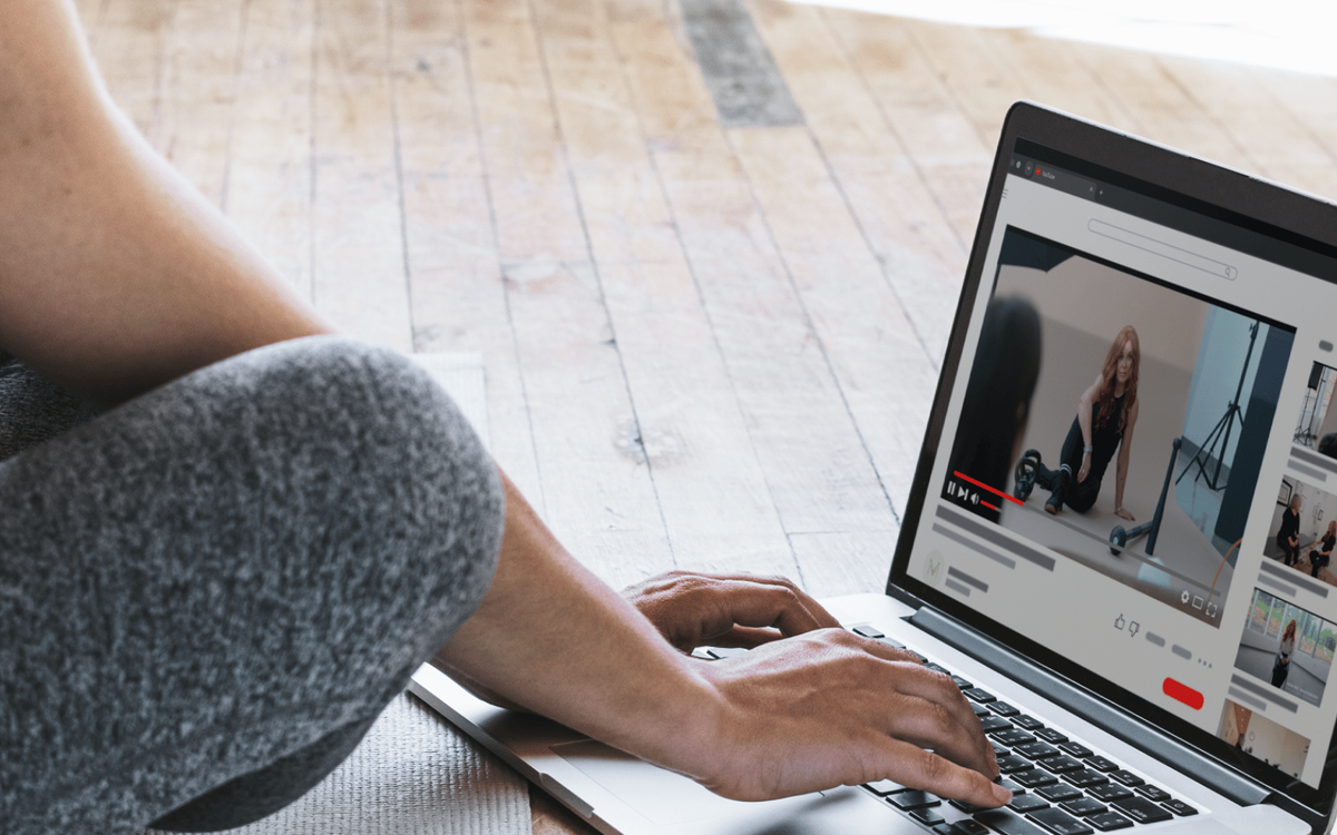 Laptop displaying a video player showing a fitness demonstration clip alongside a thumbnail sidebar of related content.