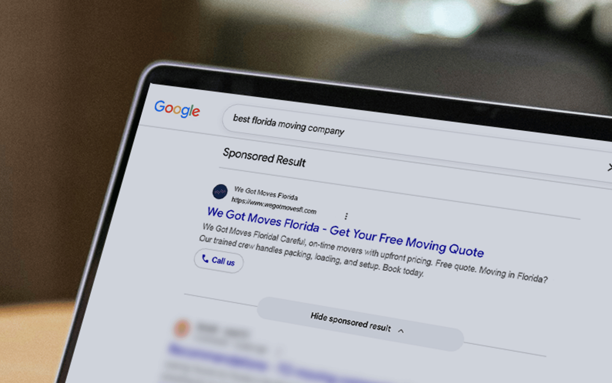 Close-up of a laptop screen showing a Google search ad for a Florida moving company with a headline, description, and call button.