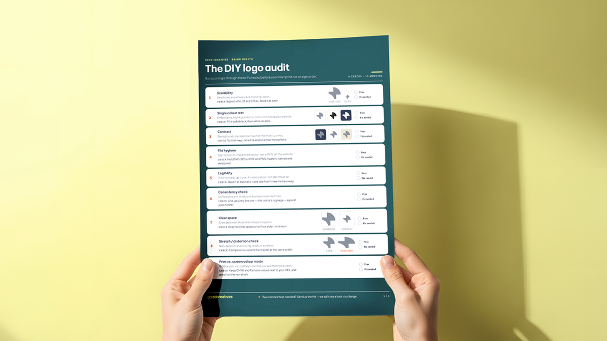A pair of hands holding a printed checklist titled 'The DIY logo audit' with 9 numbered rows of pass/fail checks, against a bright yellow background with dramatic shadow.