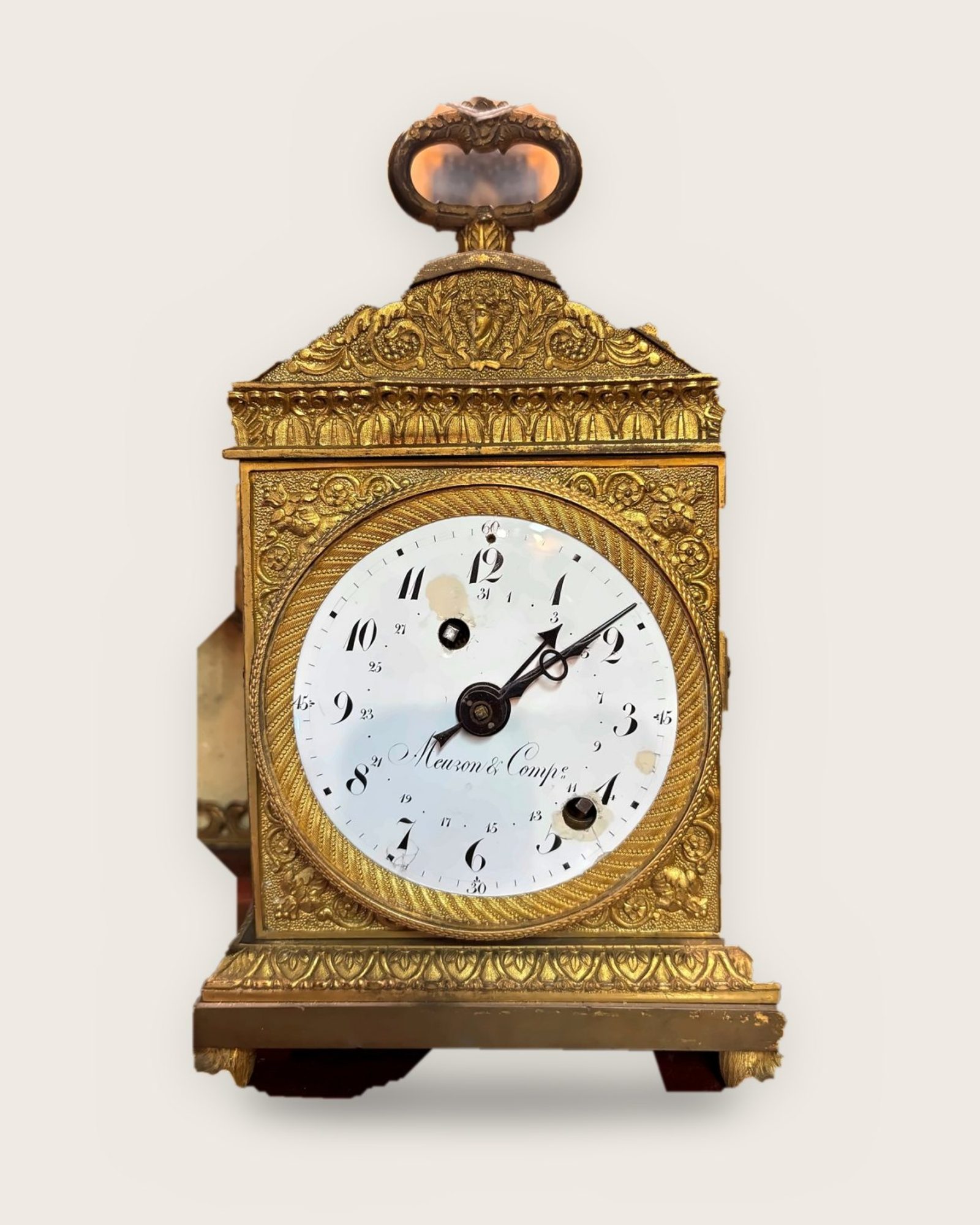 Orologio da tavolo con cassa dorata decorata e quadrante bianco firmato Meuzon & Comp.