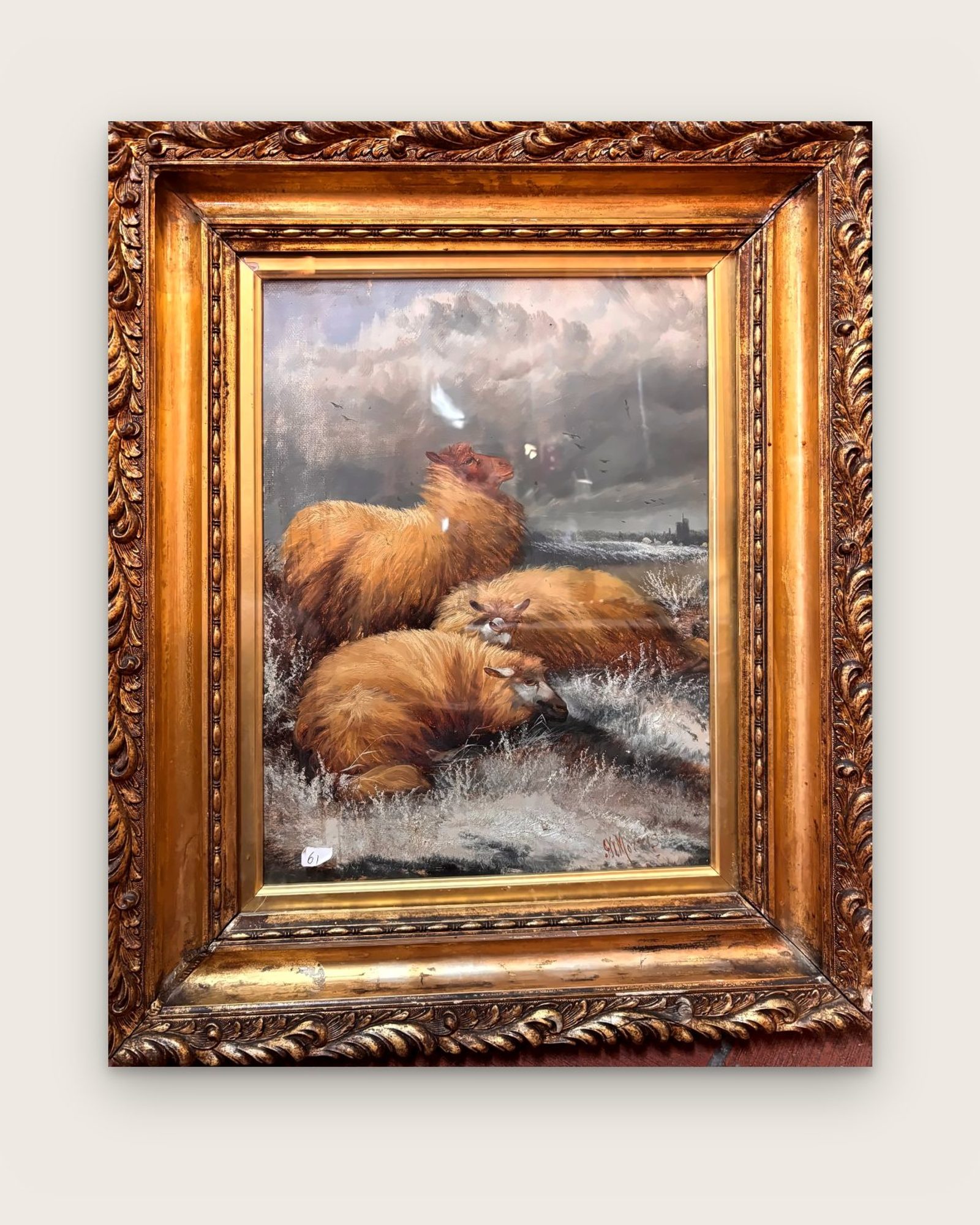 Painting of three sheep under a stormy sky, in an ornate gilded frame