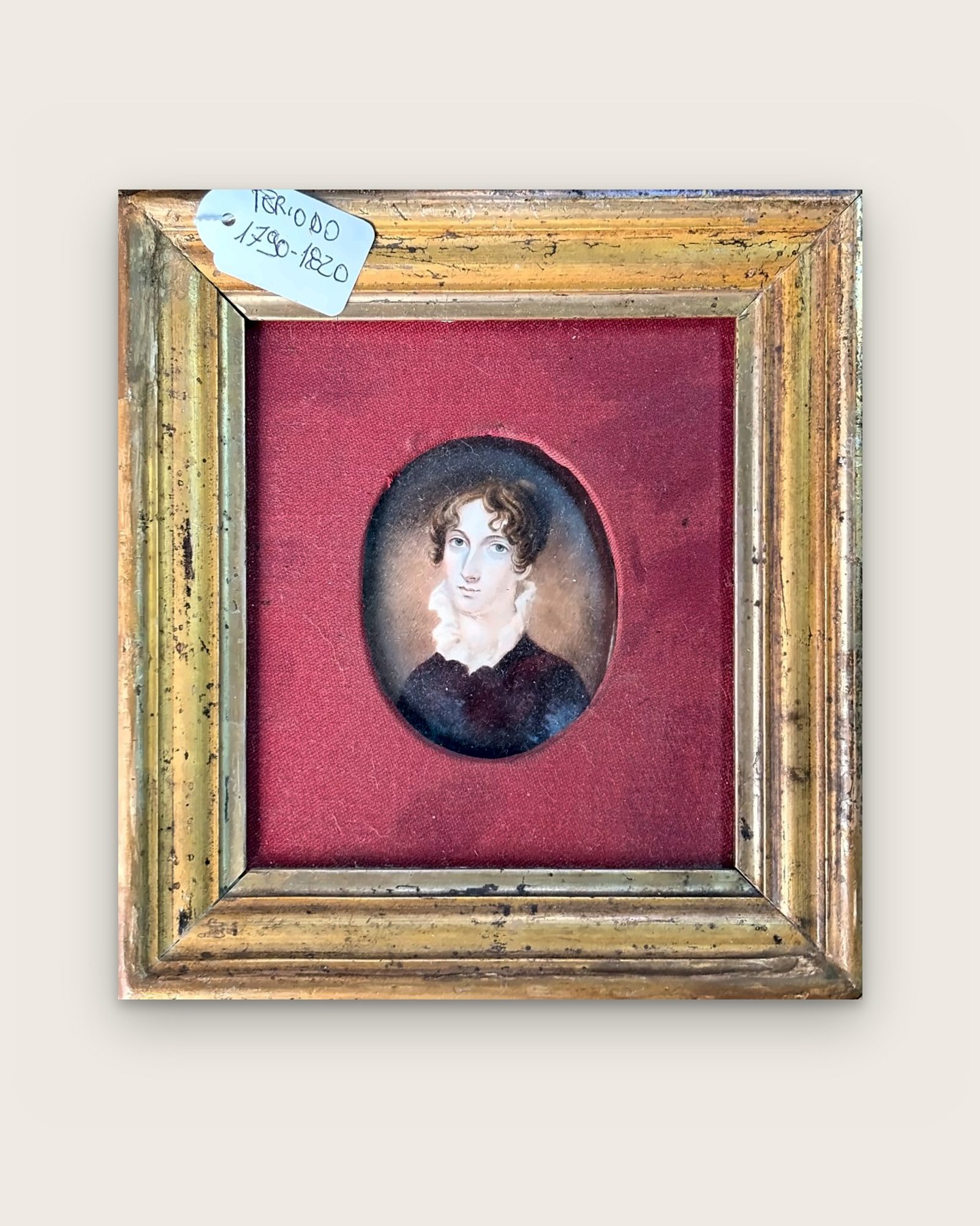 Miniatura ovale: ritratto di donna su fondo di tessuto rosso, in cornice dorata