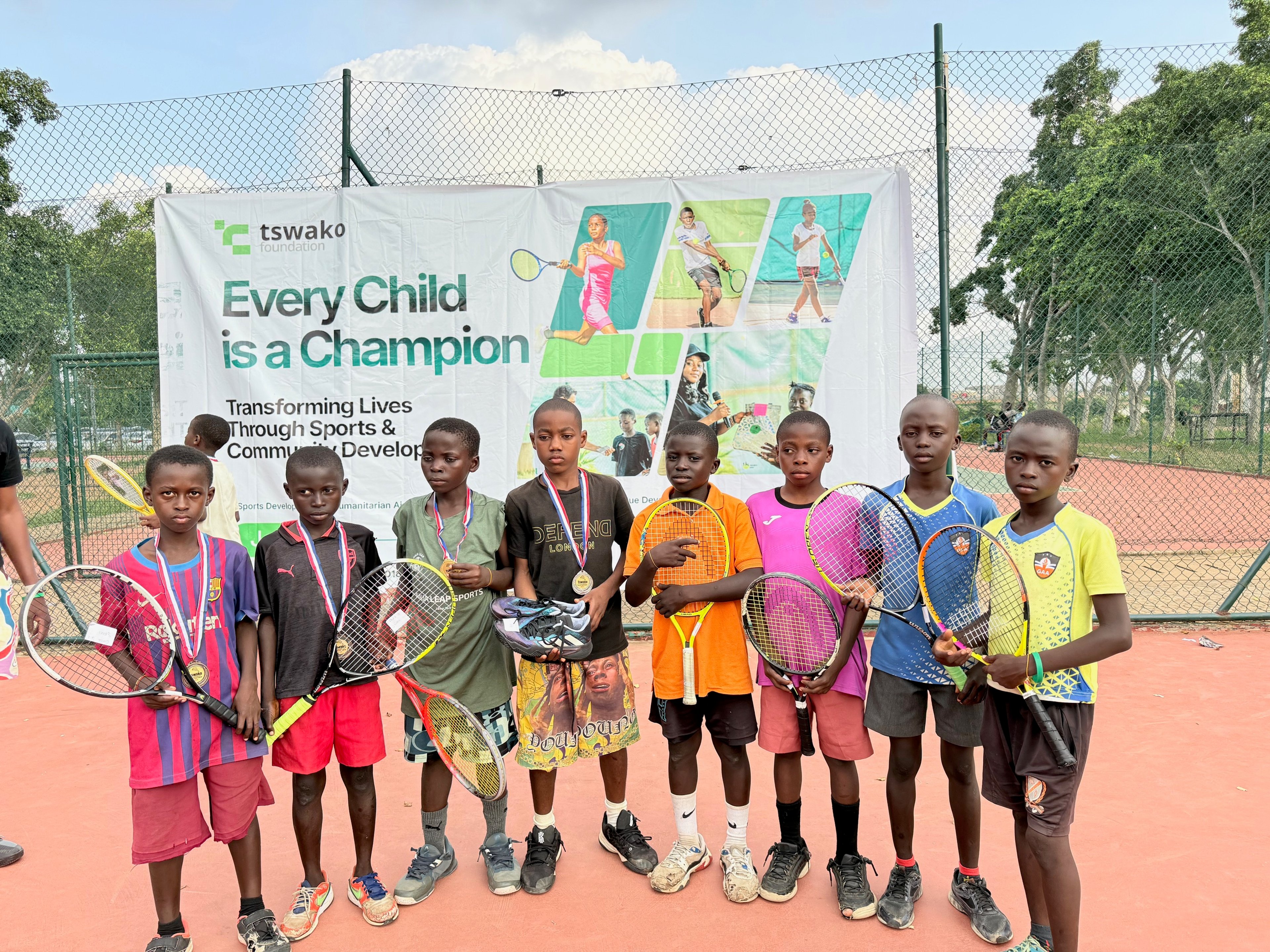 Junior medalists hold their new rackets and shoes in front of the Every Child is a Champion banner