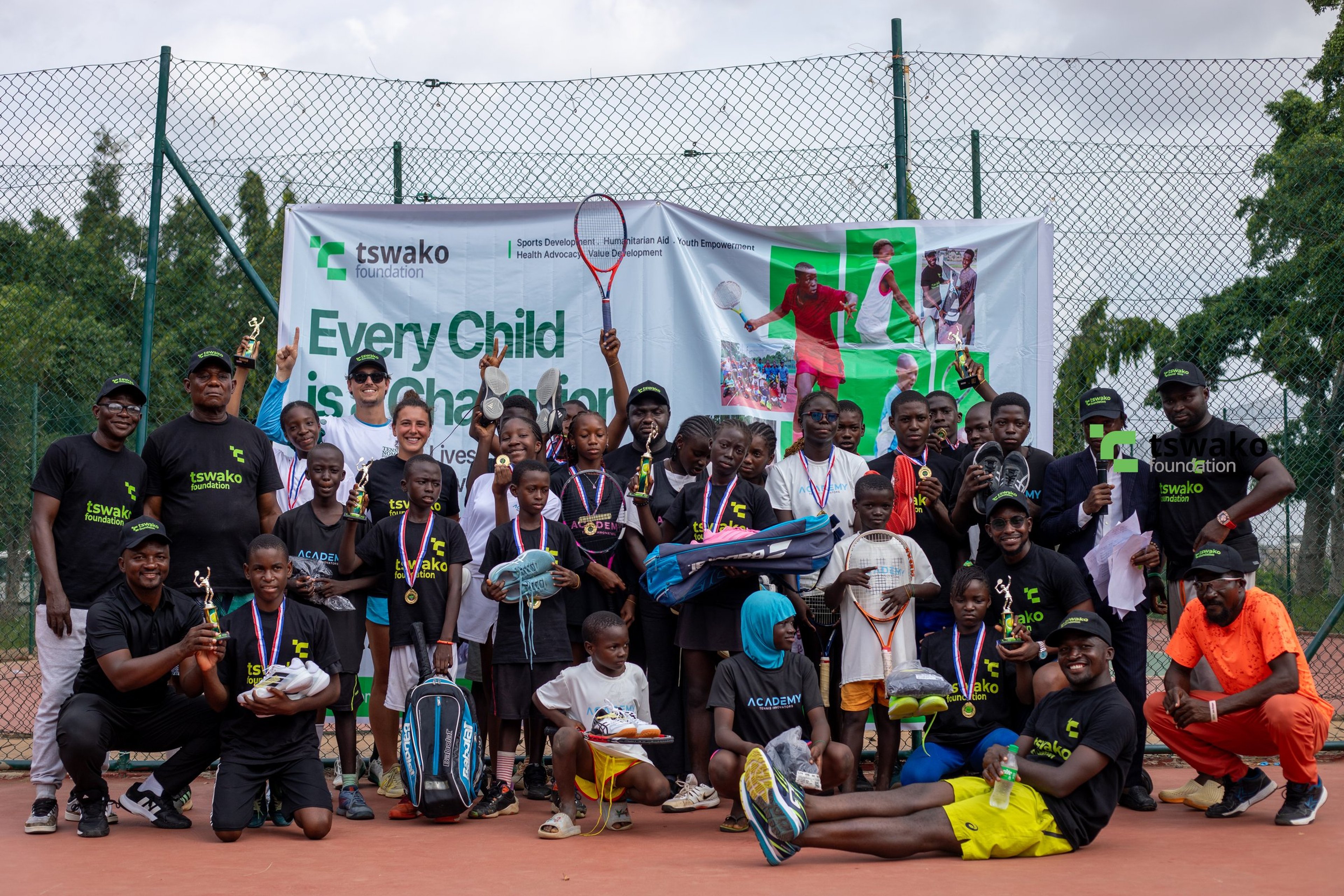 Group photo of players and coaches on court with the tournament banner