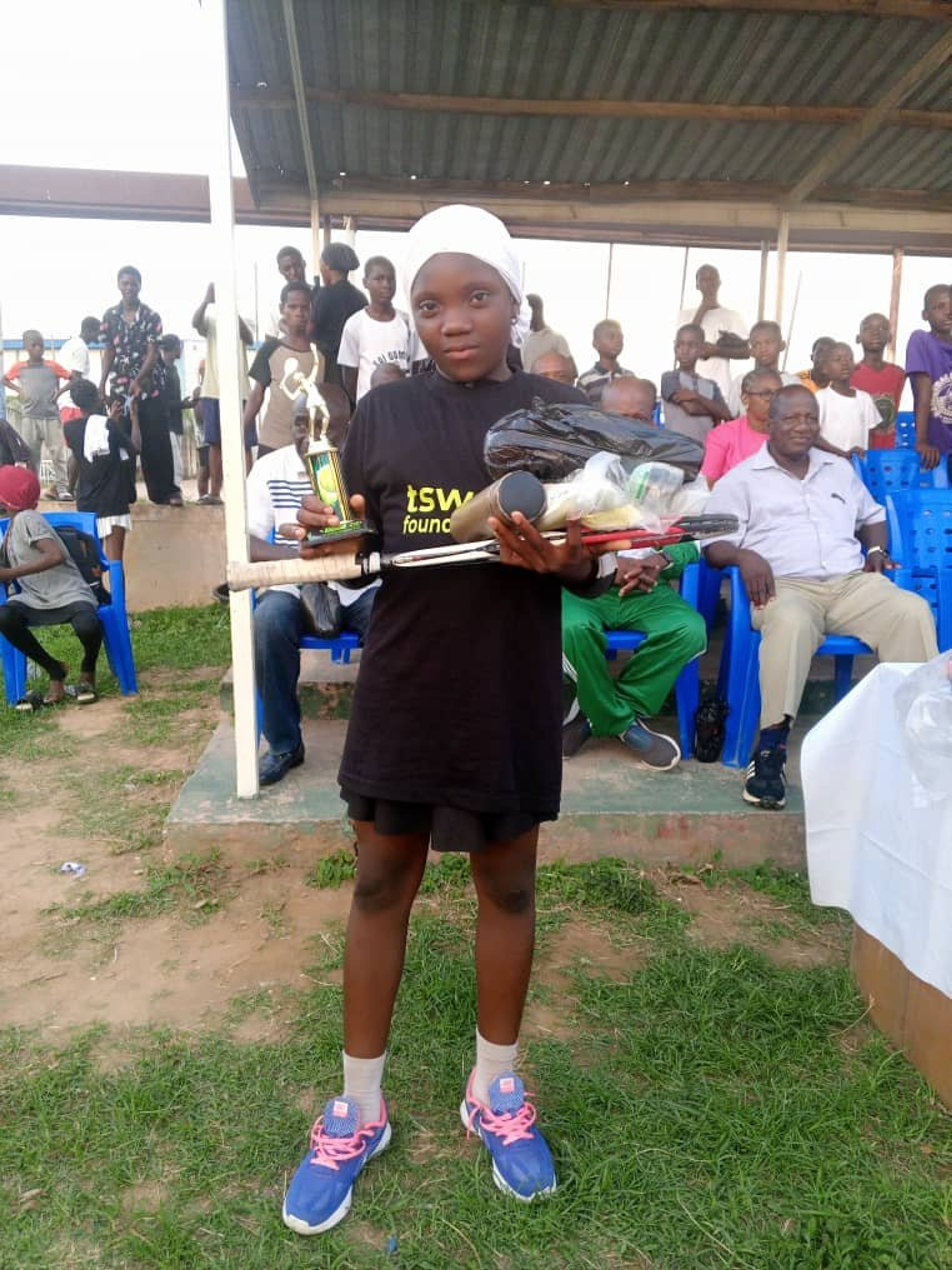Official presenting tennis gear to a smiling young player