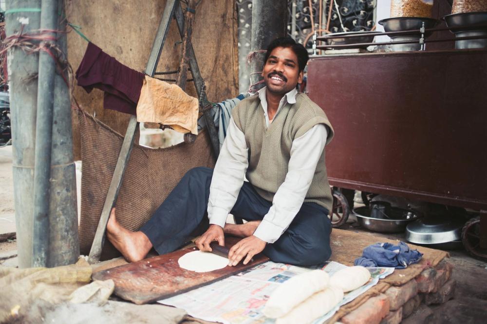 A man sits whilst rolling dough