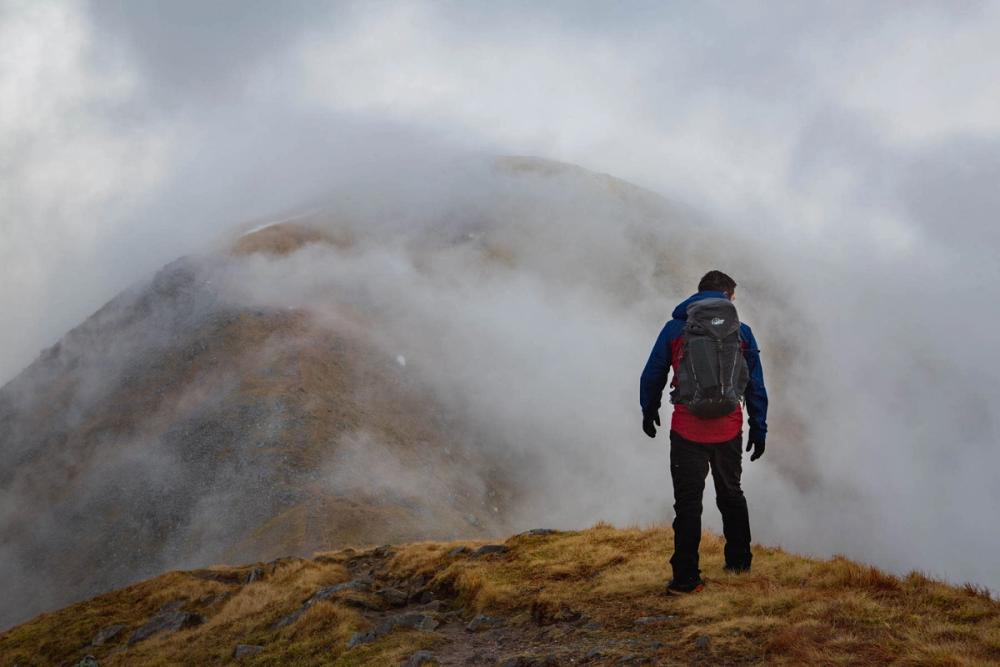 Walker in front of a cloudy hillside
