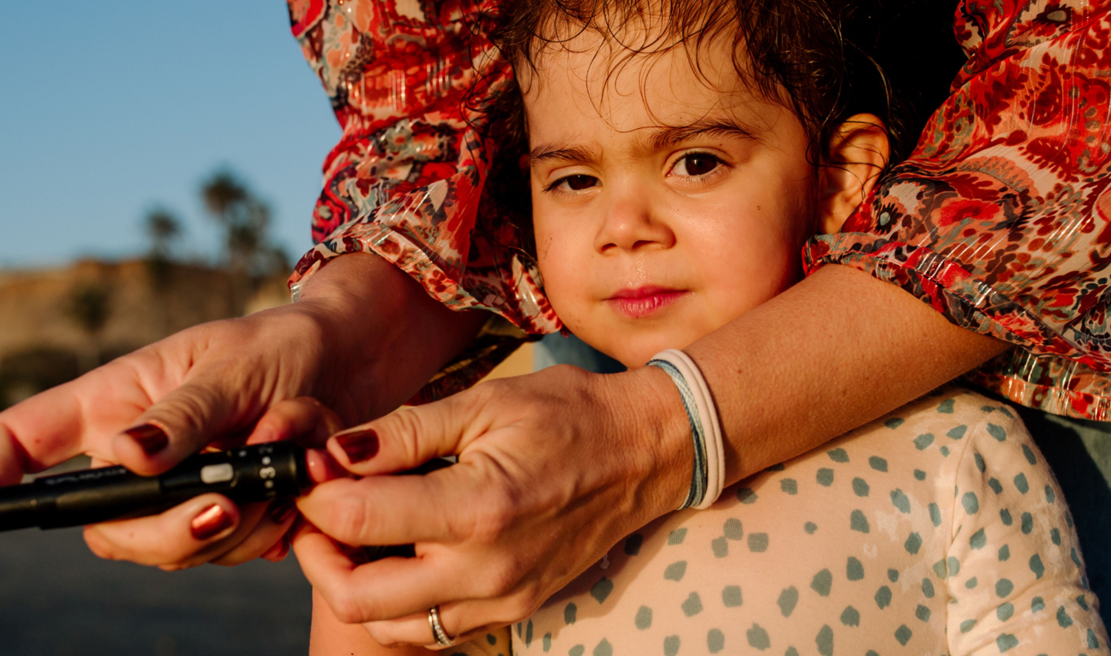 A child's blood sugar level is being checked by a woman.